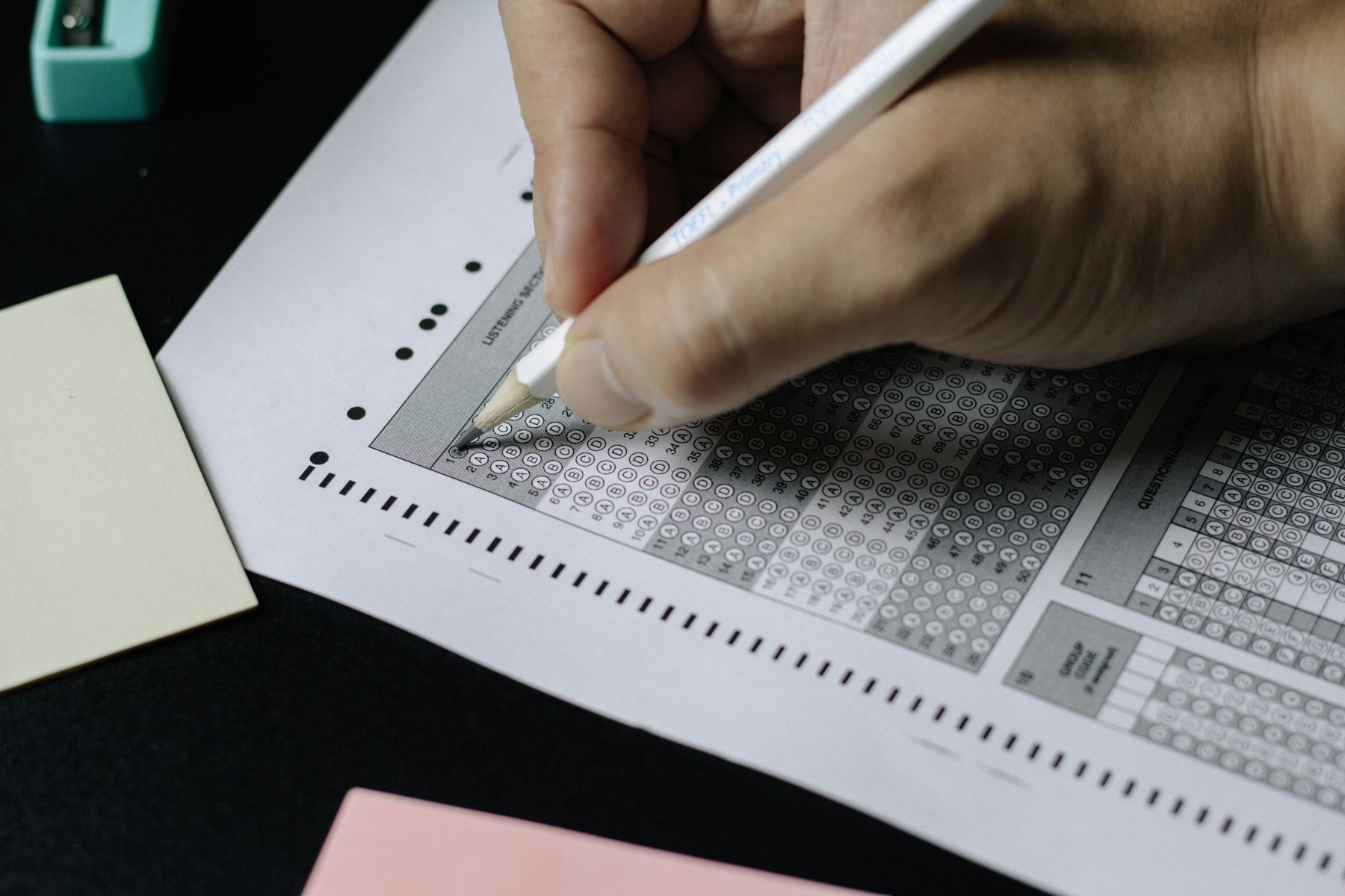 En person fyller ut et poengskjema. Bildet illustrerer automatisert scoring og vurdering.