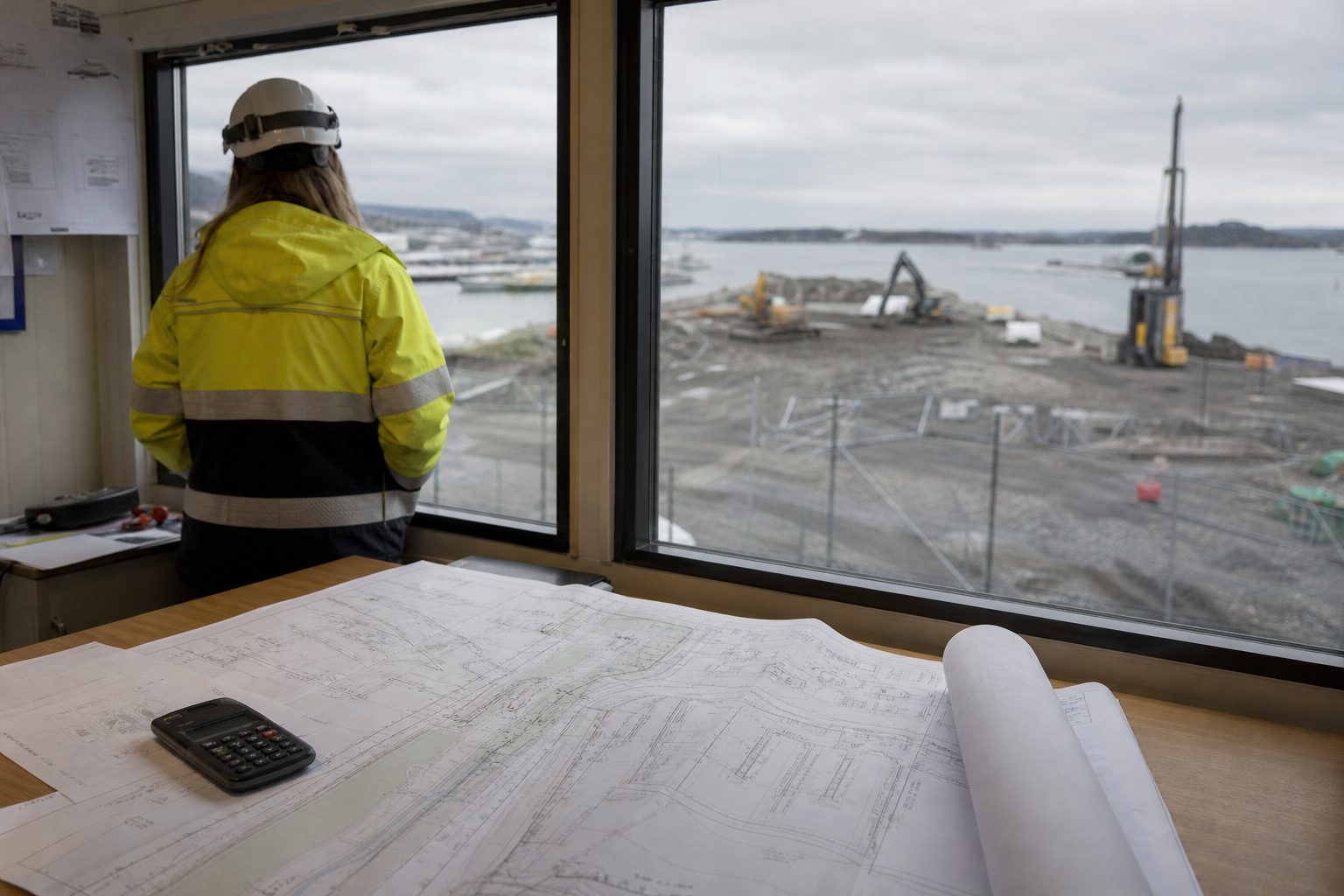 Et åpent havne- og byutviklingsområde på Filipstad i Oslo en grå høstdag, med asfaltflater, gjerder og byggeplassmaskiner foran Oslofjorden.