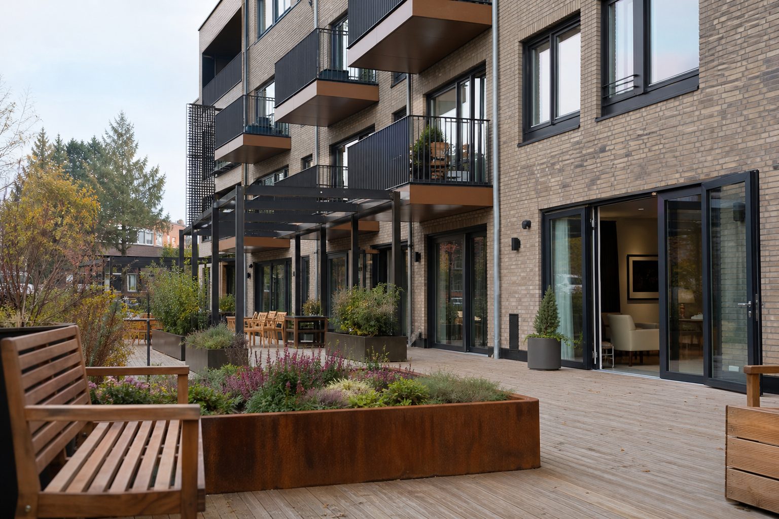 Et moderne sykehjem i Oslo sett fra en skjermet uteplass med benker, plantekasser og brede dører inn til bygget.